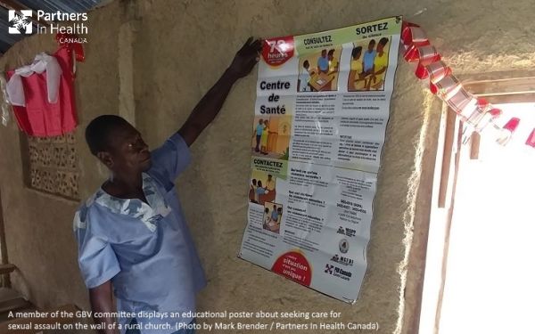 A member of the GBV committee displays an educational poster about seeking care for sexual assault on the wall of a rural church. (Photo by Mark Brender / Partners In Health Canada)