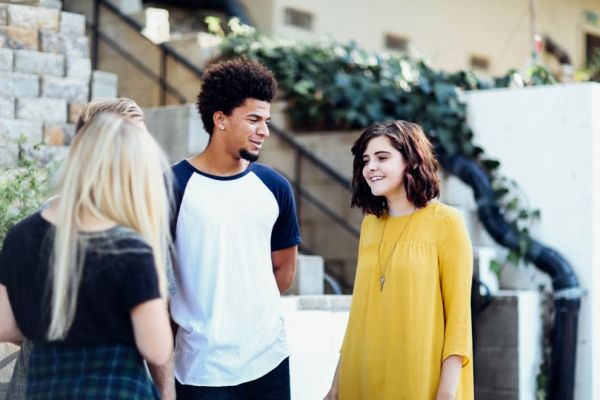 three young people standing and talking to one another